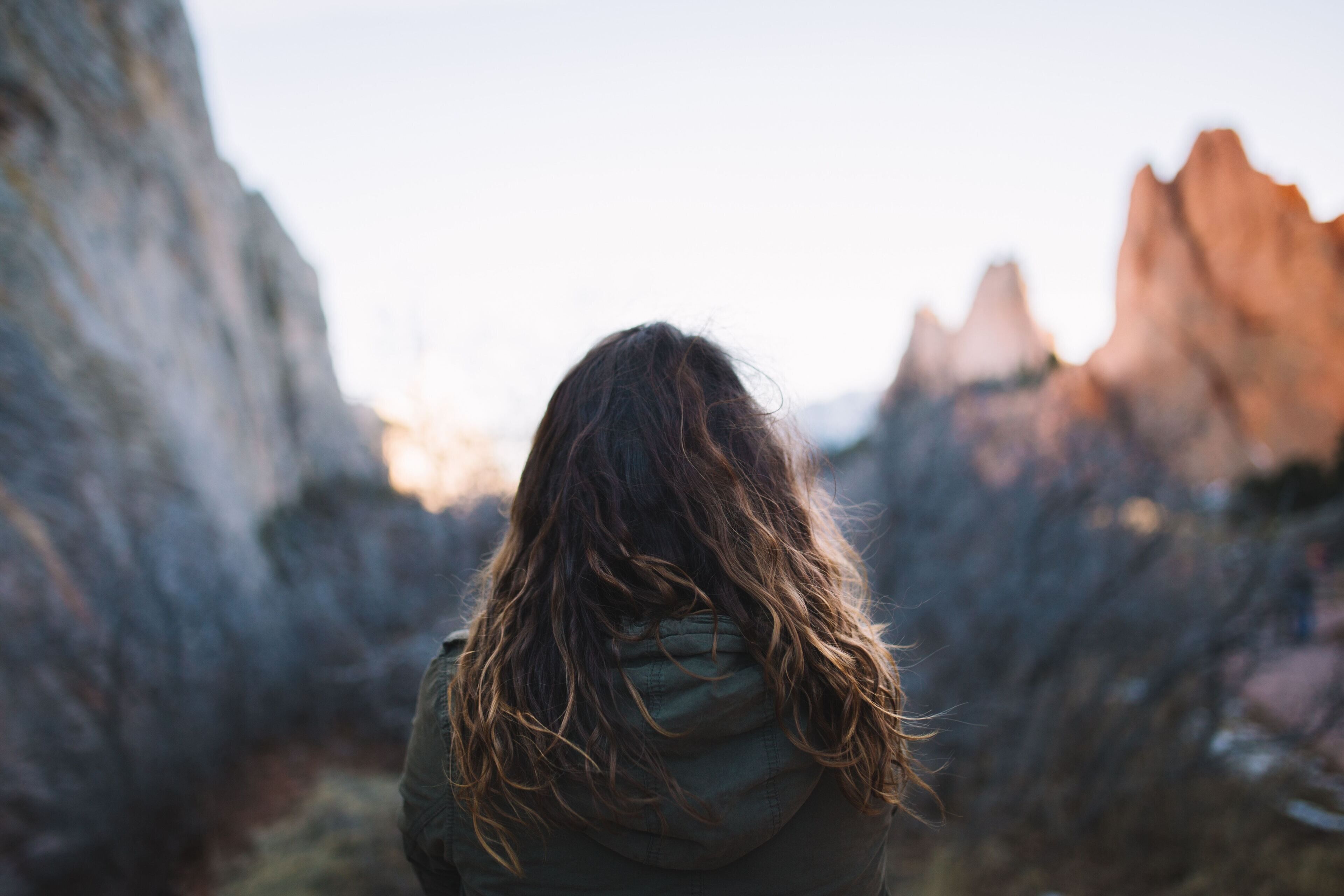 A person standing in a rocky outdoor area with a hooded jacket.