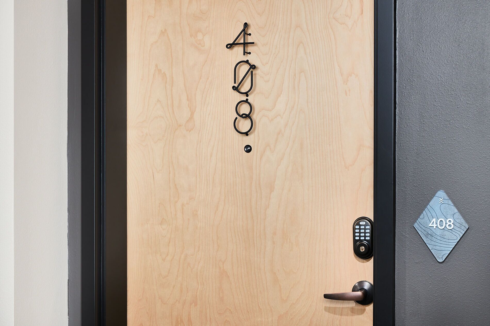 Een houten deur met het nummer 408 en een codeslot.