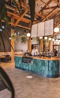 Un restaurante con interior de madera, una barra con menú y plantas colgantes.