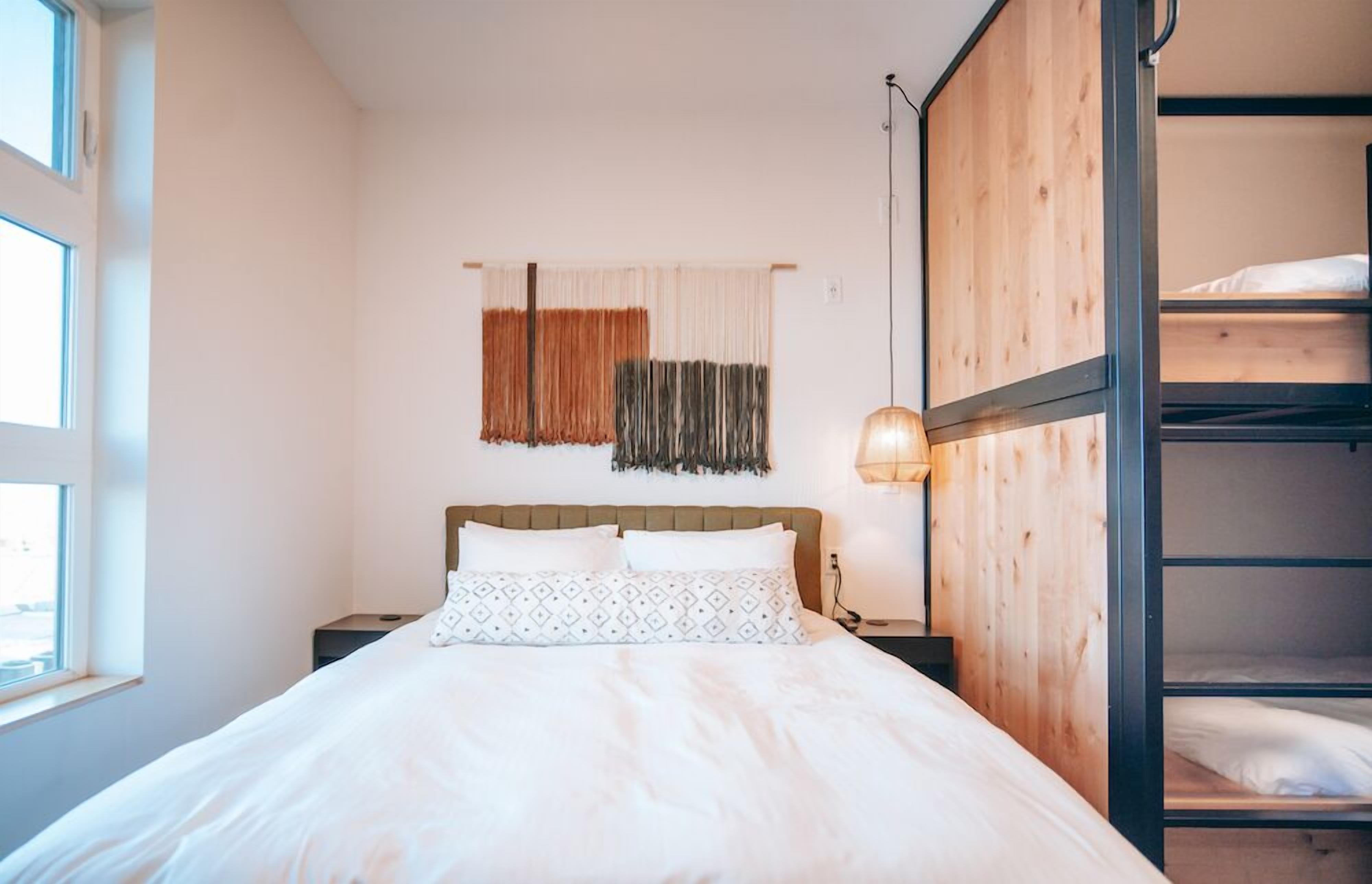 Quarto com beliche, mesa de cabeceira, abajur e janela.