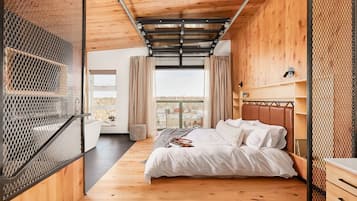 Une chambre avec un plafond en bois, un lit avec une literie blanche, une fenêtre avec des rideaux et une vue sur l’extérieur.