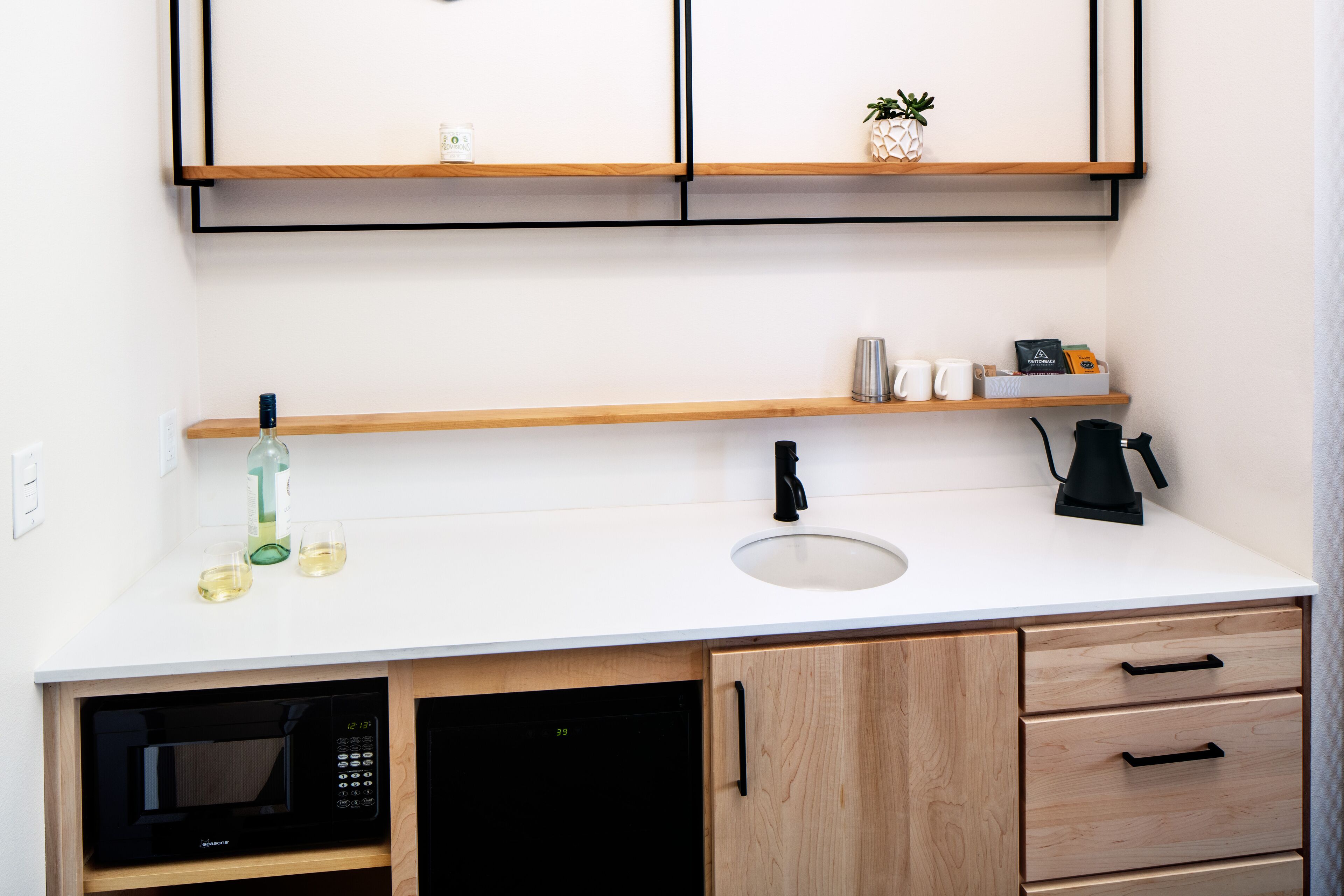 A compact kitchen with a microwave, sink, and wooden cabinets.