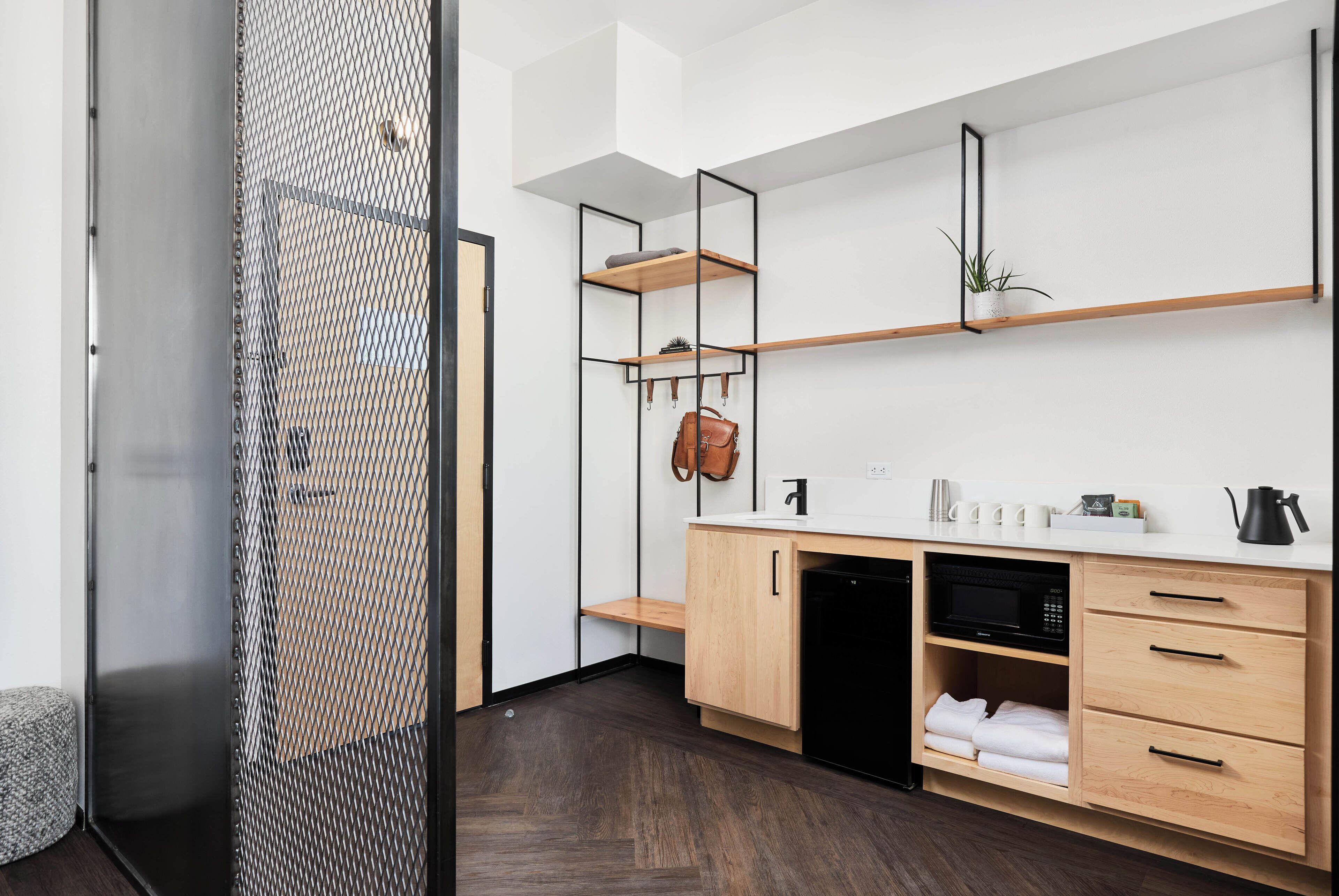 A modern kitchen with wooden cabinets, a black microwave, and a white countertop.