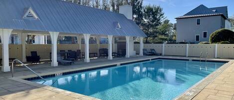 A swimming pool with a covered patio area, lounge chairs, and a building with a 'RELAX' sign.
