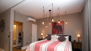A bedroom with a large bed, a ceiling light fixture, and a wall-mounted air conditioner. - Vetehuset-Skorda Quiet Loft with Private Elevator (Lindsborg)