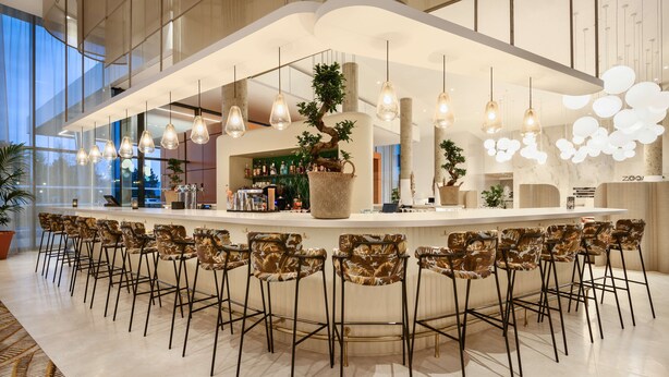 A modern bar area with a central island, multiple hanging pendant lights, and a row of bar stools. - Hyatt Place Paris Charles de Gaulle Airport (Roissy-en-France)