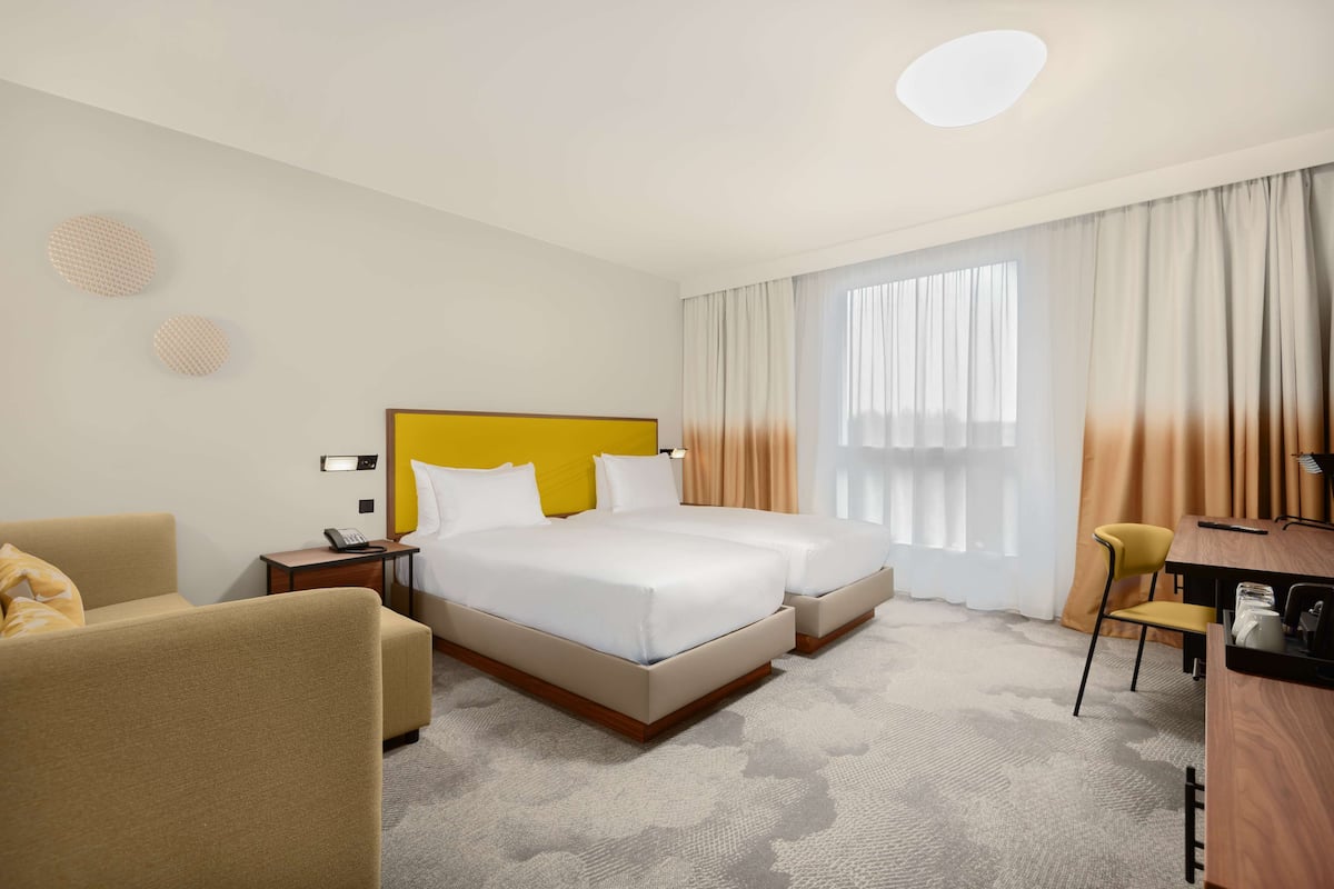 A hotel room with a double bed, a desk, a chair, and a sofa.