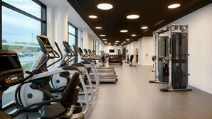 A gym with treadmills, weight machines, and a large window. - Hyatt Place Paris Charles de Gaulle Airport (Roissy-en-France)
