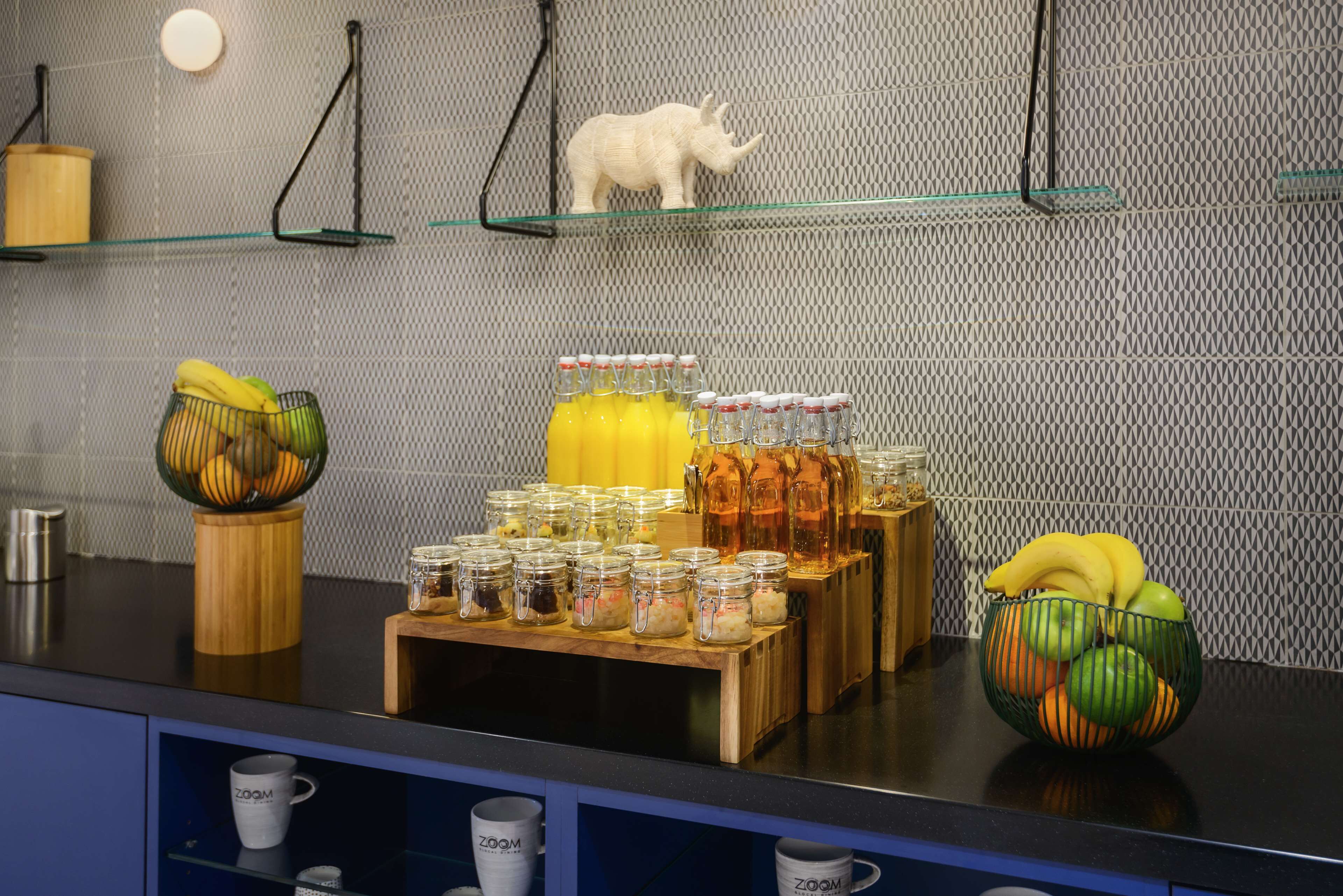Un buffet pour le petit-déjeuner proposant divers aliments, notamment des bananes, des pommes et des pots de confitures et de pâtes à tartiner.