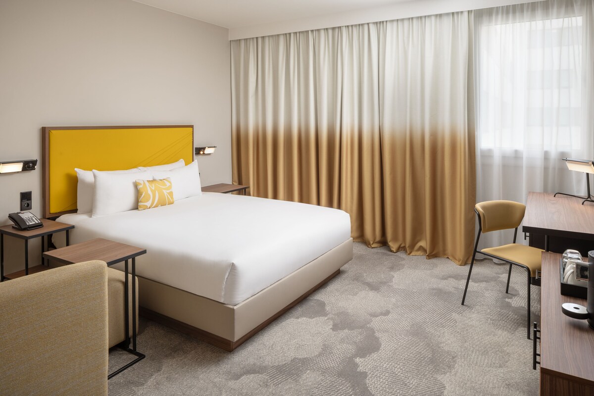 Una habitación de hotel con una cama grande, un escritorio, una silla y un teléfono en la mesita de noche.