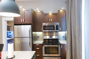 A modern kitchen with stainless steel appliances, wooden cabinets, and a granite countertop. - Vetehuset-Plantera Loft with Private Elevator (Lindsborg)