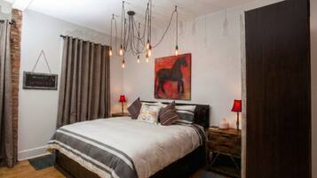 A bedroom with a bed, two bedside tables, a red lamp, a horse painting, and a sign reading 'Welcome to VETENISET'.