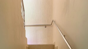 Una escalera con peldaños color beige y una barandilla de metal.