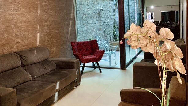 Una sala de estar moderna con un sofá marrón, un sillón rojo y una mesa de centro de vidrio.
