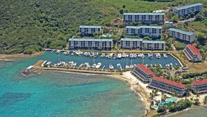 Vista aérea de um hotel à beira-mar, com vários edifícios, uma marina cheia de barcos e uma área de praia.