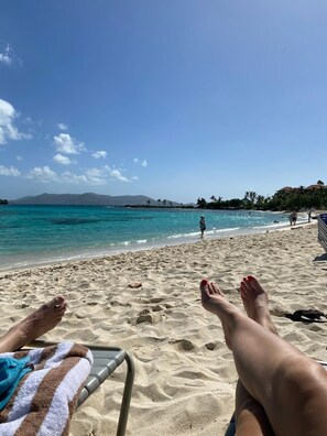 A beach scene with a clear sky, turquoise water, and a distant mountain range. - Sapphire Dreaming, Best Location! King Bed and Queen sleeper + added touches. (ST Thomas)