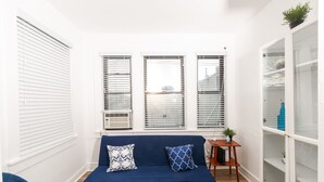 A room with a blue sofa, two patterned pillows, a small wooden side table, and a white shelving unit. - Charming and Modern! Newly renovated house close to boardwalk (Atlantic City)