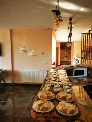 A buffet table with various food items and a microwave. - Garden Terrace Otel (Golhisar)