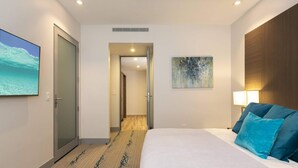 Una habitación de hotel con una cama, un cuadro, una lámpara y vistas al océano.