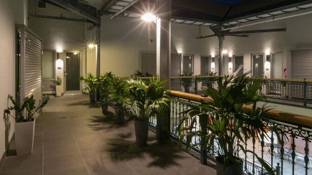 Un espacio al aire libre cubierto con plantas en macetas, piso de baldosas y barandilla.