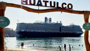 A cruise ship docked at a port with the sign "HUATULCO" above.