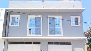 A two-story building with a flat roof, two garage doors, and multiple windows.