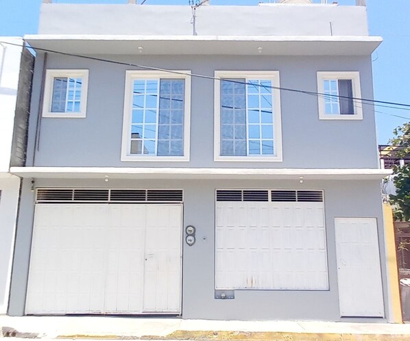 A two-story building with a flat roof, two garage doors, and multiple windows.