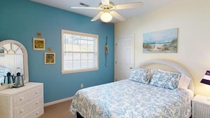 A bedroom with a bed, dresser, and a ceiling fan.