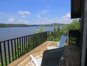 A wooden deck with two chairs overlooking a lake, surrounded by greenery and a clear sky. - 6982 Elbow CAY (Osage Beach)