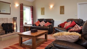 A cozy living room with a fireplace, leather sofas, and a wooden coffee table.