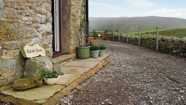 A stone building named 'Belah Barn' with a gravel driveway leading to a gate.