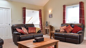 A living room with two leather sofas, a wooden coffee table, and a small wooden side table.