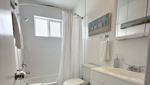 A bathroom with a bathtub, toilet, and vanity with a mirror. - Lakeside Serenity: Charming One-Bedroom Villa (Bridgman)
