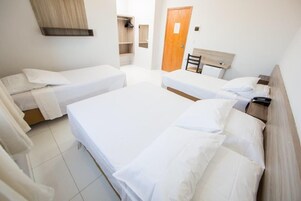 A hotel room with two single beds, a wooden headboard, a small desk, and a wardrobe.