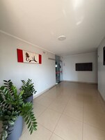 Un pasillo amplio con una planta en maceta, una obra de arte colgada en la pared y una puerta que da a otra habitación.