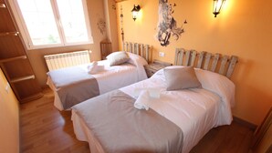 Ein Schlafzimmer mit zwei Betten, Holz-Kopfteilen, einem Heizkörper und Wandleuchten.