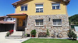 Ein zweistöckiges Haus mit gelber Fassade, einem steinernen Unterteil und einem roten Ziegeldach.