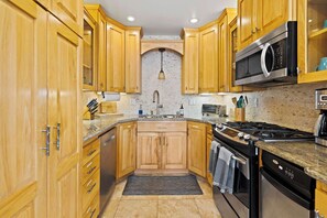 Kitchen features a double sink, range hood, microwave, dishwasher, oven, and gas range.