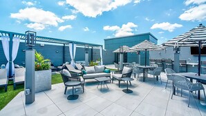 An outdoor patio area with a pool, lounge chairs, and umbrellas. - Luxury Furnished Apartments by Hyatus Downtown at Yale (New Haven)