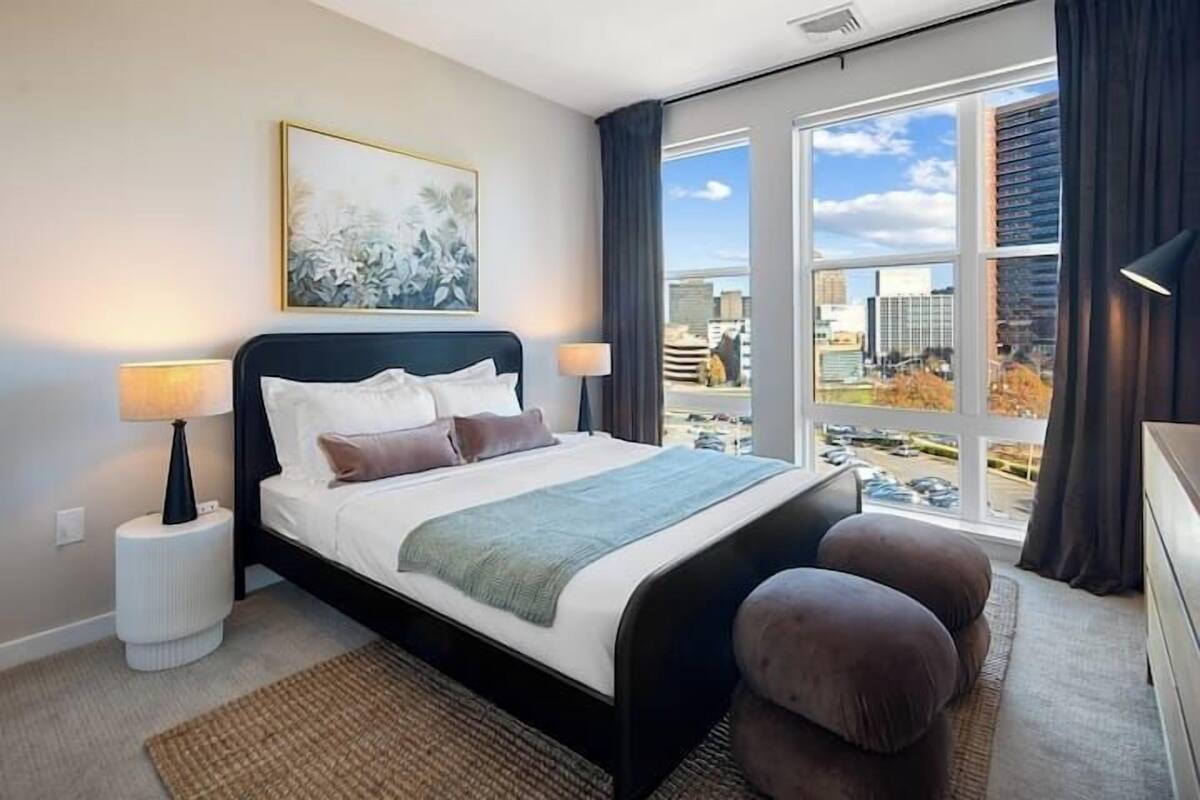 A modern hotel room with a large bed, a view of the city, and a cityscape visible through the window.