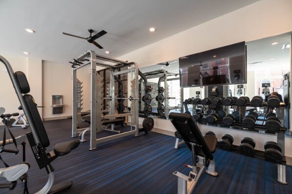 Un gimnasio con equipamiento de ejercicio, un espejo y una televisión.