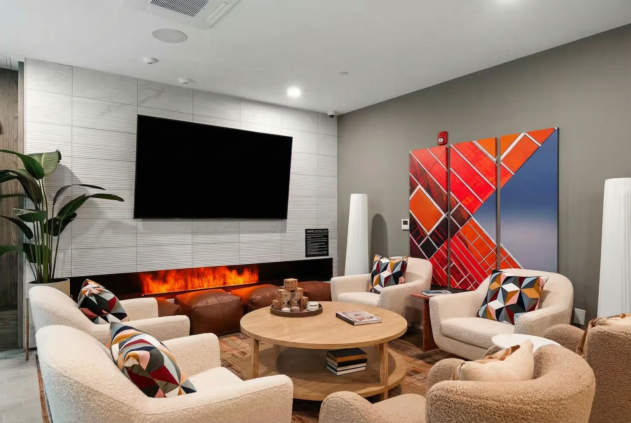Una sala de estar moderna con chimenea, asientos cómodos y un televisor grande montado en la pared.