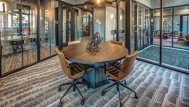 A conference room with a round table, chairs, and glass walls. - Luxury Furnished Apartments by Hyatus Downtown at Yale (New Haven)