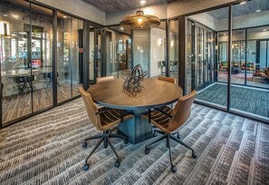 A conference room with a round table, chairs, and glass walls.