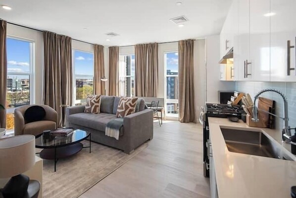 Una sala de estar moderna con sofá, mesa de centro y vistas a la ciudad.