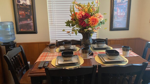 A dining table set with plates, bowls, and a vase of flowers. - "WELCOME TO ARTHUR’S PLACE! IDEAL FOR LARGE GROUPS AND PET FRIENDLY."  (Baton Rouge)