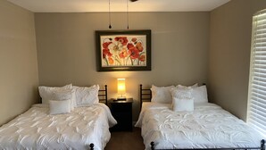 A bedroom with two beds, a ceiling fan, a nightstand with a lamp, and a painting on the wall. - "WELCOME TO ARTHUR’S PLACE! IDEAL FOR LARGE GROUPS AND PET FRIENDLY."  (Baton Rouge)