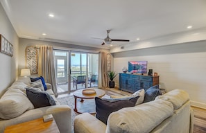A spacious living room with a large sofa set, a coffee table, and a television. - 11B Mariners Walk by AvantStay | Direct Beach Access! | Views | Communal Pool (Isle Of Palms)