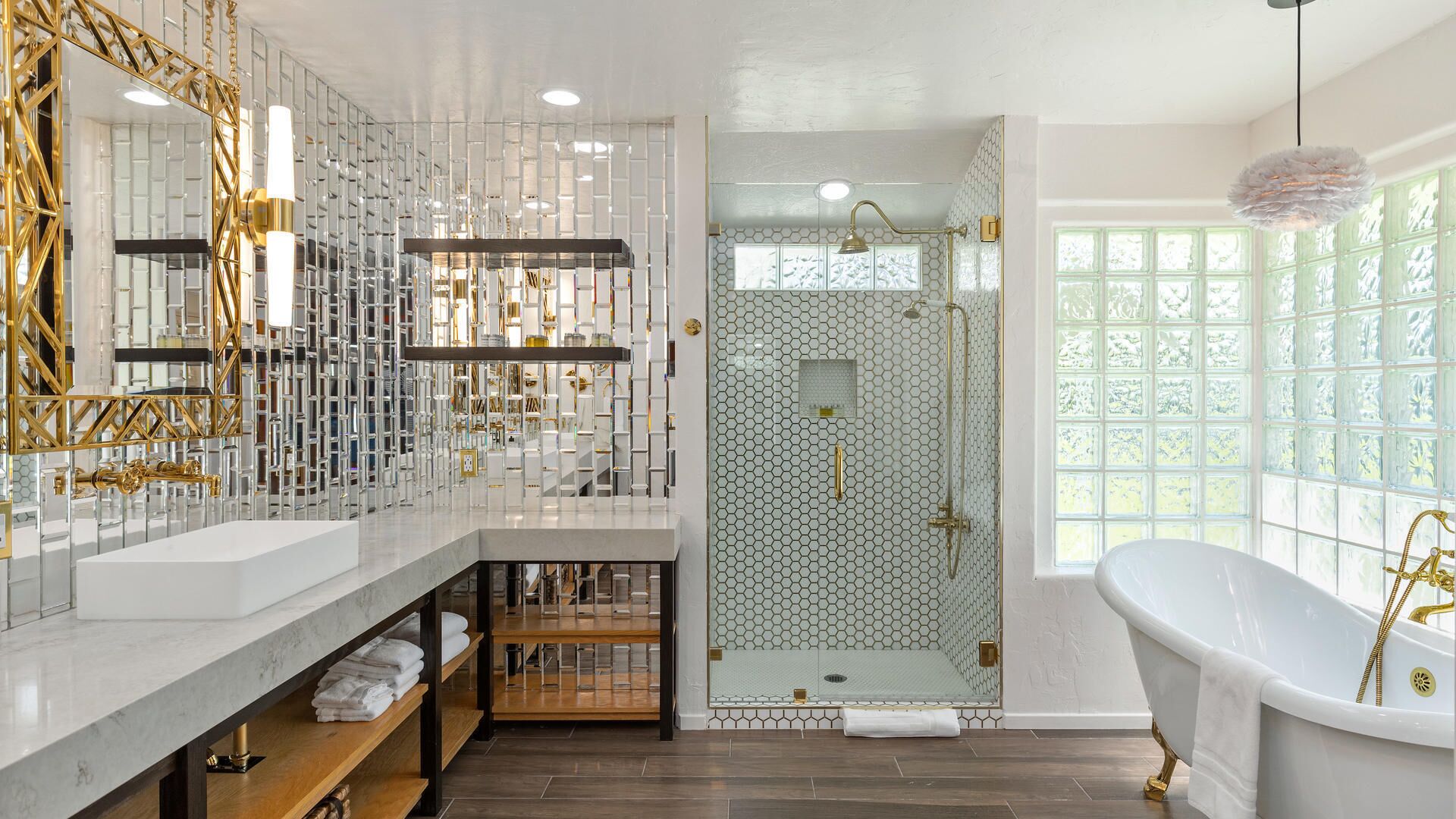 A luxurious bathroom with a large white bathtub, a glass-enclosed shower, and a vanity with a mirror and shelves.