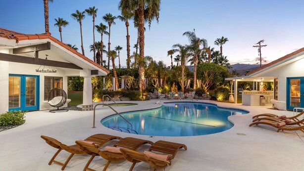 Un área de piscina con sillones reclinables, un jacuzzi y una zona de bar.